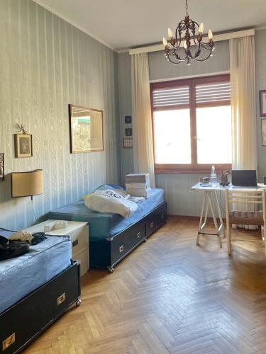 a bedroom with two beds and a table and a chandelier at Casa di Charme lungo Po in Turin