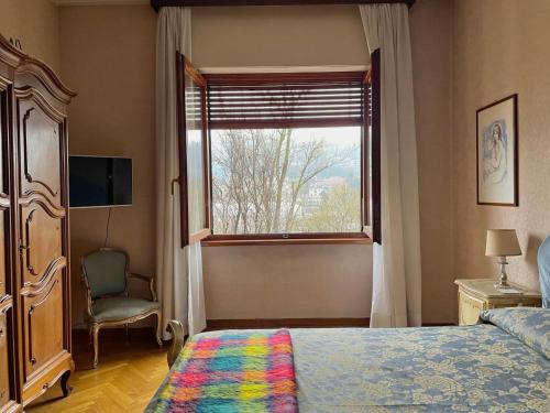 a bedroom with a bed and a window and a chair at Casa di Charme lungo Po in Turin