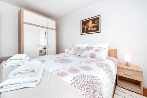 a white bedroom with a large bed with a window at Apartman Oly in Rovinj