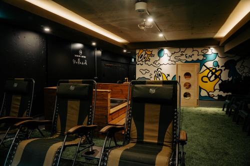 a room with chairs and graffiti on the wall at EN PLUS Sauna and Capsule Bed 男性専用 in Kochi