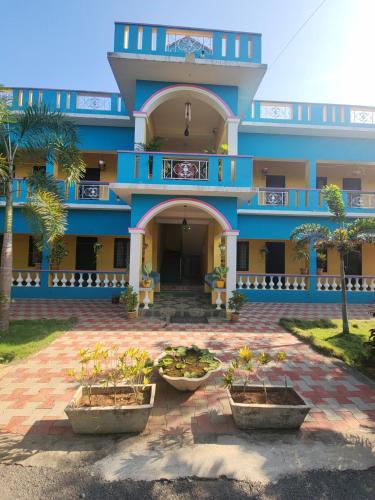 a blue building with three potted plants in front of it at Paradise Forest Resort in Puducherry