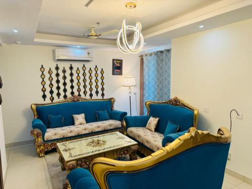 ein Wohnzimmer mit 2 blauen Sofas und einem Tisch in der Unterkunft Downtown haven in Mohali