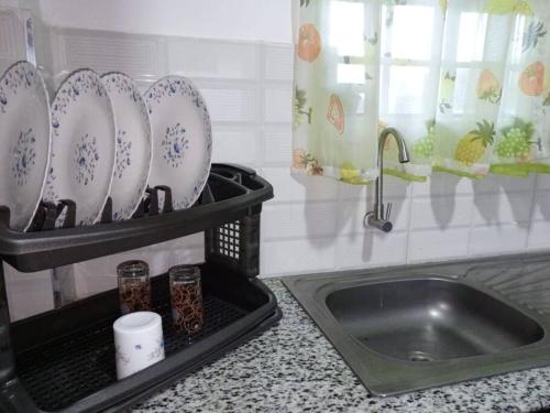 um balcão de cozinha com um lavatório e pratos numa prateleira em VillaRoma's Urban Retreat A Stylish Warm Loft em Eldoret