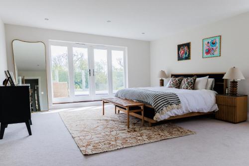 een slaapkamer met een groot bed en een spiegel bij 4BD Luxurious Countryside Retreat Scenic Views in Worplesdon