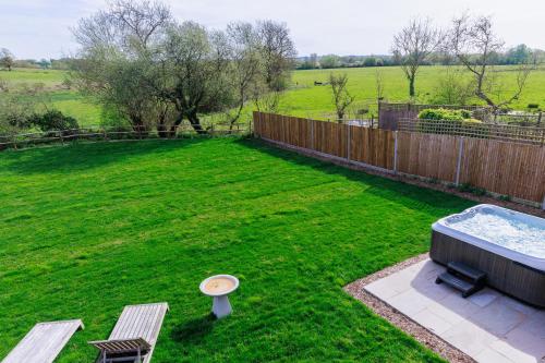a backyard with a hot tub and two benches at 4BD Luxurious Countryside Retreat Scenic Views in Worplesdon