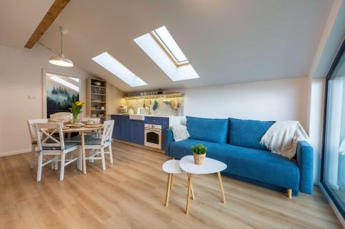 a living room with a blue couch and a table at Apartamenty Nad Wisłą - z sauną i blisko centrum - Dream Apart in Ustroń