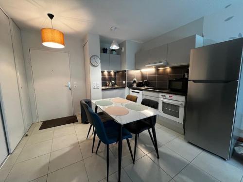 une cuisine avec une table, des chaises et un réfrigérateur dans l'établissement T2 avec jardinet parking la genette, à La Rochelle