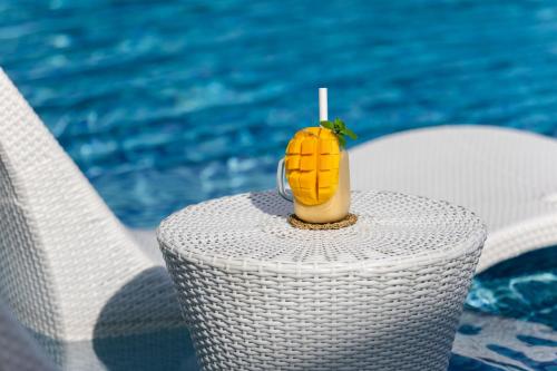 a pineapple drink sitting on a table next to a pool at La Joya Farm Resort & Spa in Aloguinsan
