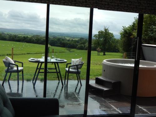 a room with a tub and a table and chairs at The Lodges at Thornbrook in Ingleton 