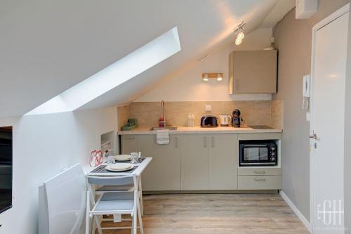 une cuisine avec des armoires blanches et une table dans l'établissement Sakura - Face Gare, à Tours