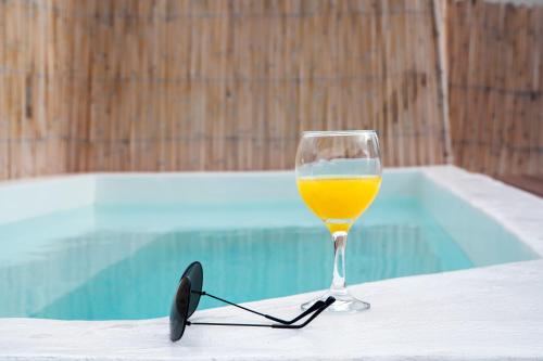 a glass of wine sitting on a table next to a pool at Santorini Rooftop Hot Tub Suite with Panoramic Views in Akrotiri