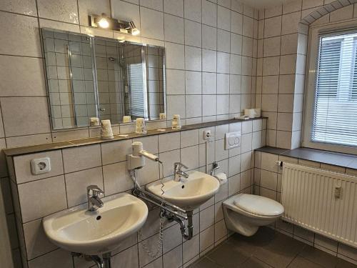 a bathroom with two sinks and a toilet and a mirror at Hotel Hirsch Günzburg in Günzburg