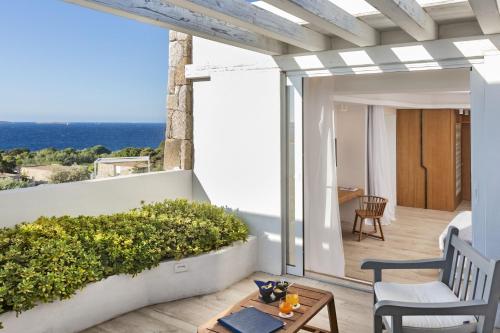 balcón con mesa y vistas al océano en Hotel Grand Relais Dei Nuraghi, en Baja Sardinia