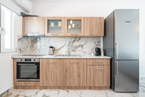 a kitchen with wooden cabinets and a refrigerator at Punta Mare Villa 4 in Karpathos Town