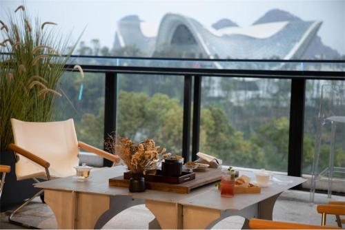 einen Tisch und Stühle vor einem großen Fenster in der Unterkunft Riverside Wing Hotel Guilin in Guilin
