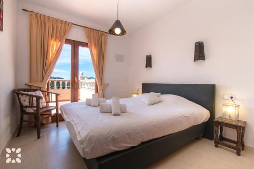 a bedroom with a bed with white sheets and a balcony at Villa Octavio by Abahana Villas in Benitachell