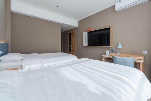 a hotel room with two beds and a flat screen tv at Home Inn Zhangjiajie Tianmen Mountain Branch in Zhangjiajie