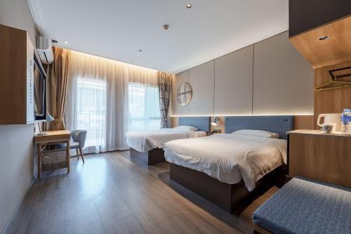 a hotel room with two beds and a desk at Home Inn Zhangjiajie Tianmen Mountain Branch in Zhangjiajie