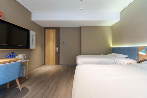 a hotel room with two beds and a flat screen tv at Home Inn Zhangjiajie Tianmen Mountain Branch in Zhangjiajie
