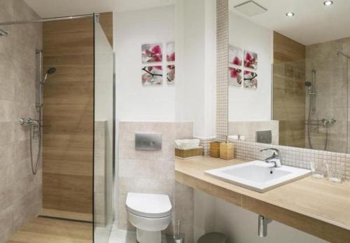 a bathroom with a toilet and a sink and a shower at Apartamenty Triton Park in Warsaw