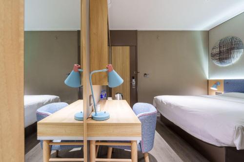 a bedroom with a bed and a desk with a lamp at Home Inn Zhangjiajie Tianmen Mountain Branch in Zhangjiajie