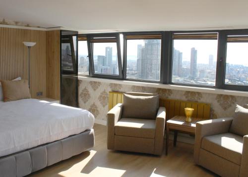 una camera con un letto e due sedie e finestre di Aram Otel Business & Luxury a Istanbul