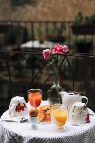 a table with a white table cloth with drinks and flowers at Palais Aoma, hôtel particulier de luxe en Provence in LʼIsle-sur-la-Sorgue