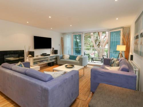 a living room with two blue couches and a tv at 5 Red Sails in Poole