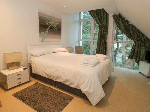 a bedroom with a large white bed with windows at 5 Red Sails in Poole