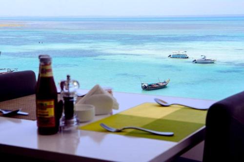 SunSeaBar Beach Resort في كيندوا: طاولة مع زجاجة من البيرة وإطلالة على المحيط