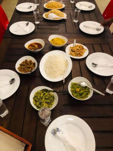 a wooden table topped with plates and bowls of food at Lotus cool hotel and restaurant in Ibbagomuwa