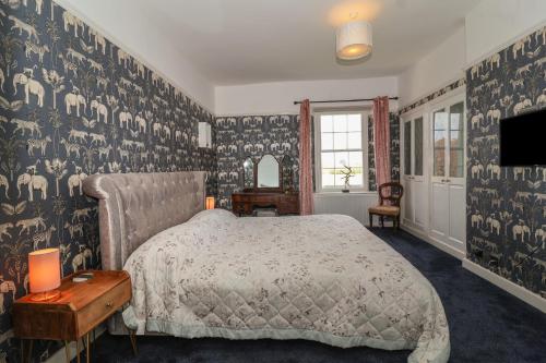 1 dormitorio con cama y pared con papel pintado en Buckland House, en Taunton