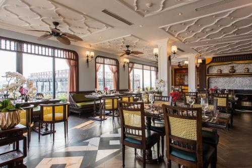 a dining room with tables and chairs and windows at Hanoi Tirant Hotel in Hanoi