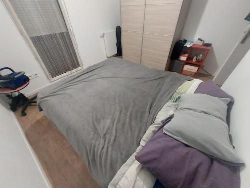 une chambre avec un grand lit avec des oreillers dessus dans l'établissement Appartement JO Stade de France, à Aubervilliers