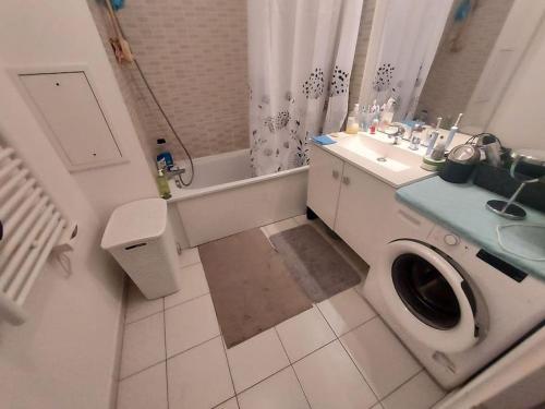 une salle de bain avec une machine à laver et un lavabo dans l'établissement Appartement JO Stade de France, à Aubervilliers