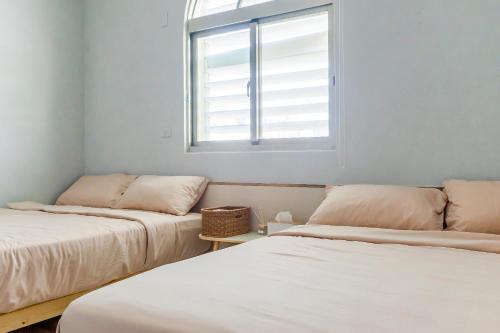 two beds in a room with a window at Ocean Diary Hostel in Green Island