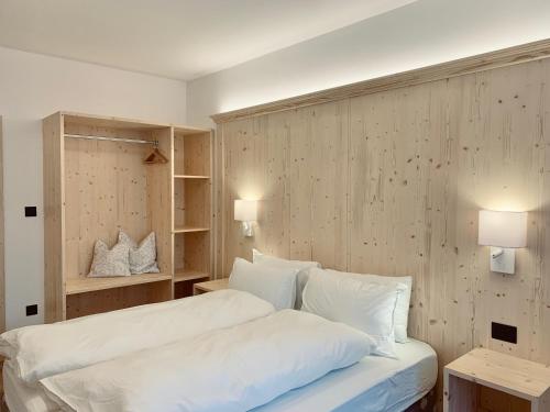 a bedroom with a bed with white sheets and pillows at Cesa Do Ruf eurochalet in Campitello di Fassa