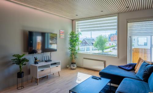 a living room with a blue couch and a tv at Arctic Homes - Premium Aurora Apartment in Tromsø