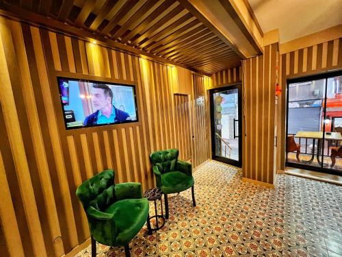 um quarto com cadeiras verdes e uma televisão na parede em Taksim Cetinkaya Suite em Istambul
