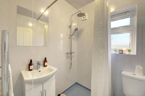 a white bathroom with a shower and a sink at Stunning and Lovely 3 Bed House - Catch 22 in Coventry