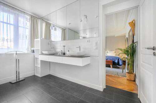 une salle de bain blanche avec deux lavabos et un miroir dans l'établissement Trocadéro Signature, à Paris