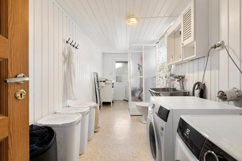 a white bathroom with a washing machine and a sink at Boukersen Heim in Tromsø