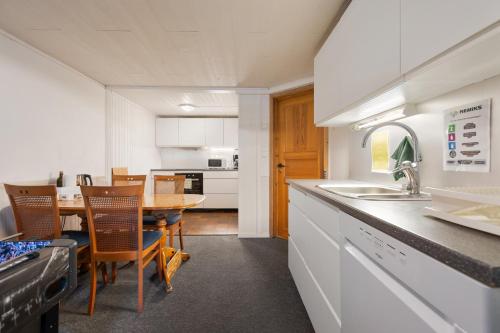 a kitchen with a sink and a table with chairs at Boukersen Heim in Tromsø