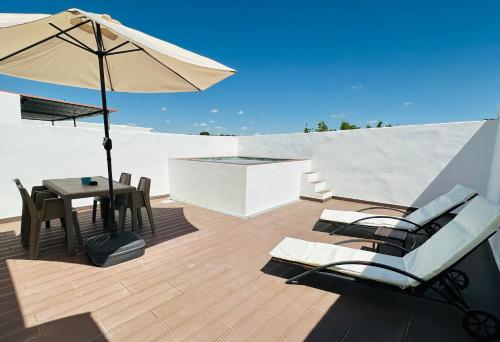 a patio with a table and an umbrella and chairs at Pátio 7 & Meio DiscoverAlentejo in Moura