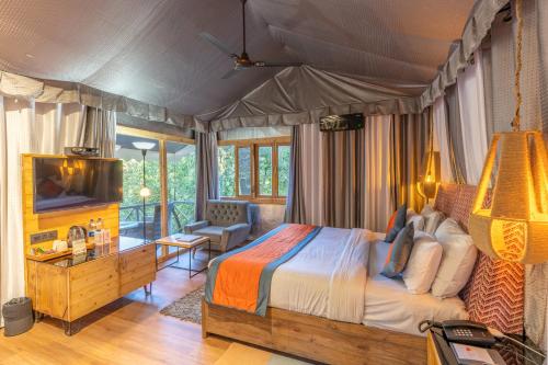 a bedroom with a bed and a tv in it at Ayar Jungle Resort in Nainital