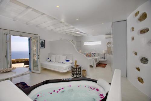 um quarto branco com uma banheira e um sofá em Diana Villa Mykonos em Agios Ioannis