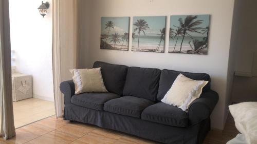 a blue couch in a living room with three paintings on the wall at Apartamento golf del sur in Santa Cruz de Tenerife