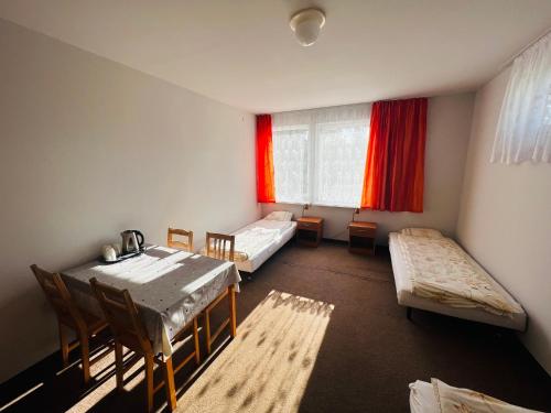 a room with two beds and a table and chairs at Wakacyjna Wioska in Ustronie Morskie