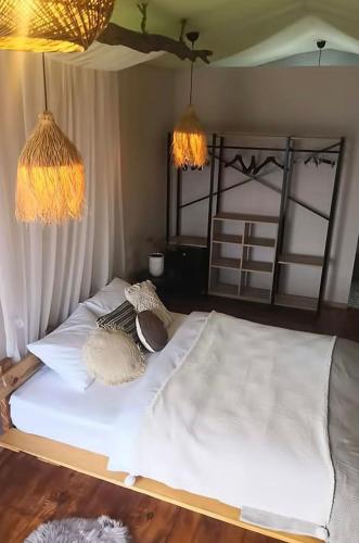1 cama con sábanas blancas y almohadas en una habitación en Veranda Glamping, en Ayvacık