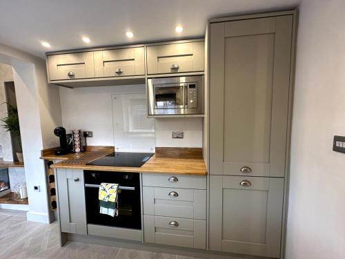 uma cozinha com armários brancos e um forno com placa de fogão em Deluxe Stays @ Libra Spaces em Hull